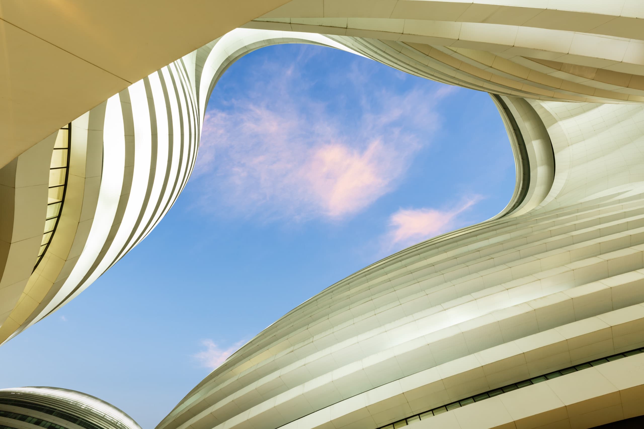 Curved white architectural facade framing a clear blue sky